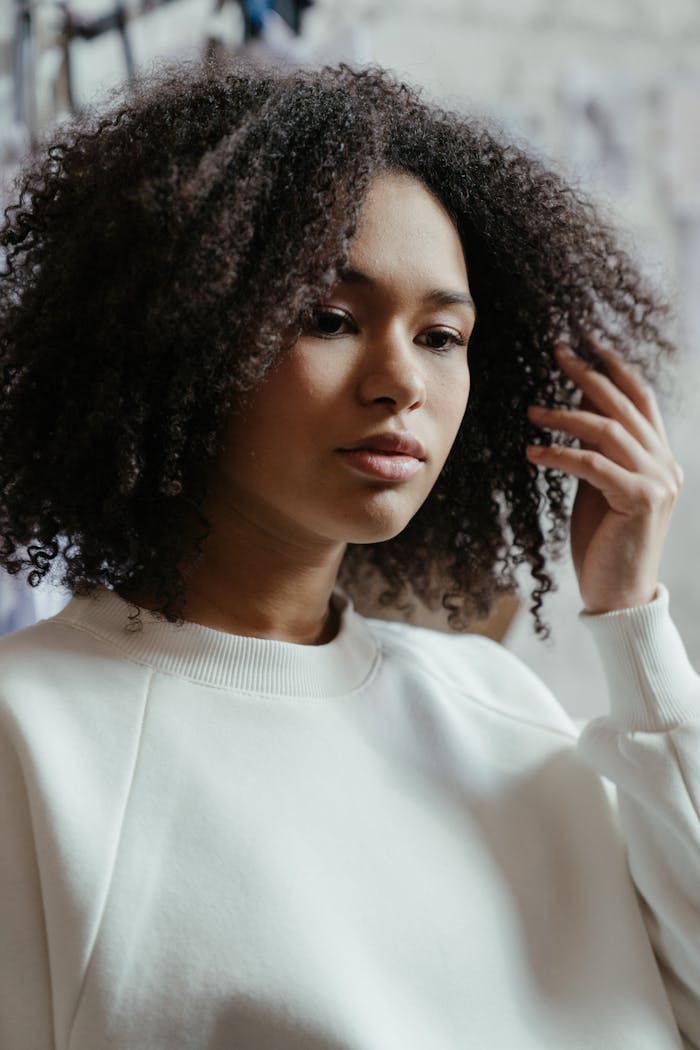 Close-up of a woman with curly hair in a stylish outfit showcasing natural beauty.